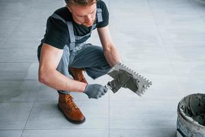 uomo nel grigio uniforme lavori con piatto in casa nel moderno grande ufficio a giorno foto