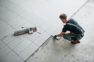 superiore Visualizza di uomo nel grigio uniforme quello installazione piatto in casa nel moderno grande ufficio a giorno foto