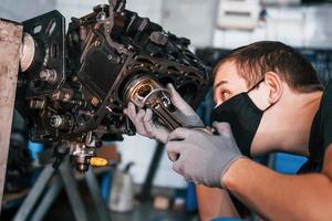 professionale riparatore nel nero protettivo maschera lavori con rotto automobile motore foto