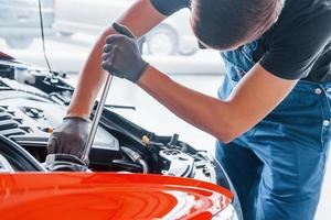 uomo nel uniforme lavori con rotto automobile. concezione di auto servizio foto