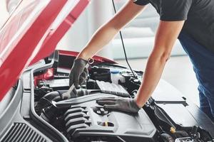 uomo nel uniforme lavori con rotto automobile. concezione di auto servizio foto