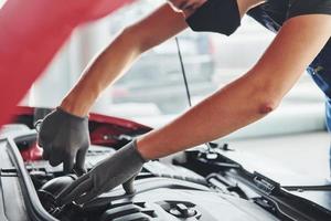 uomo nel uniforme lavori con rotto automobile. concezione di auto servizio foto