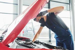 uomo nel uniforme e nero protettivo maschera lavori con rotto automobile. concezione di auto servizio foto