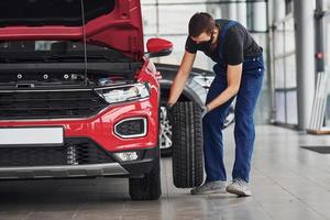 uomo nel uniforme mutevole pneumatico di automobile. concezione di auto servizio foto