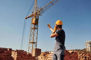 comunicare con gru tipo. costruzione lavoratore nel uniforme e sicurezza attrezzatura avere lavoro su edificio foto