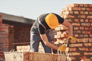 occupato con mattone parete. costruzione lavoratore nel uniforme e sicurezza attrezzatura avere lavoro su edificio foto