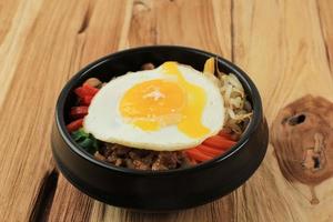 bibimbap con soleggiato lato uovo su un' di legno sfondo foto