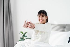 contento donna allungamento sua braccia su il letto nel il mattina. foto