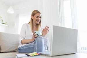 giovane donna agitando a il computer portatile e parlando per sua amici attraverso video chiamata, ragazza alunno parlando di video conferenza chiamata, femmina insegnante allenatore tutoraggio di webcam, in linea addestramento, e-coaching concetto foto