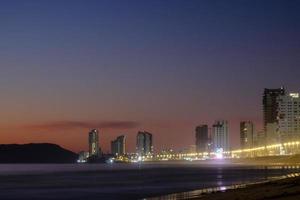 mazatlàn sinaloa spiaggia a notte con luminoso città nel il sfondo foto