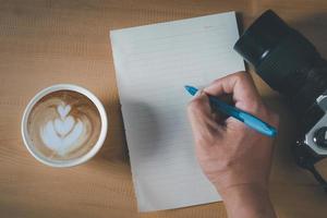 superiore Visualizza di vuoto carta, caffè tazza, telecamera e penna su il di legno tavolo foto