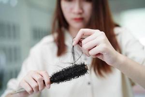 la donna asiatica ha problemi con la caduta dei capelli lunghi attaccata alla spazzola del pettine. foto