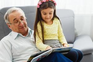 nipotina e nonno Guardando fotografie insieme nel un' foto album a casa