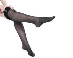 donna mette su calze autoreggenti su sua bellissimo lungo gambe, isolato su bianca sfondo foto
