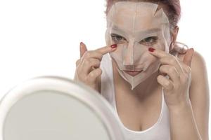 cosmetico procedura. donna di viso con bianca cosmetico maschera foto