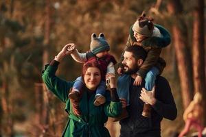 madre e padre con loro poco figlio avere un' camminare nel primavera foresta a giorno foto