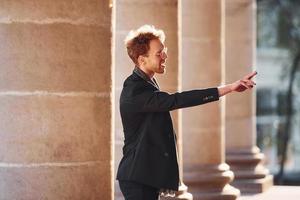 parlando per qualcuno. elegante giovane uomo nel formale di classe Abiti all'aperto nel il città foto