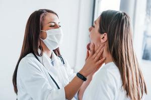 controllo linfa nodi e gola. giovane donna avere un' visitare con femmina medico nel moderno clinica foto