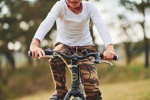 giovane ragazzo equitazione il suo bicicletta all'aperto nel il foresta a giorno foto