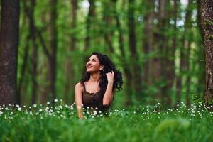 positivo brunetta nel casuale Abiti seduta nel il foresta a giorno foto