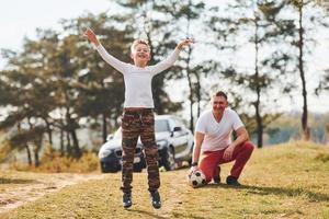 giocando calcio. padre con il suo figlio la spesa fine settimana insieme all'aperto vicino foresta a giorno foto