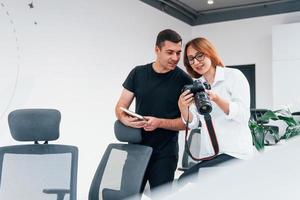 uomo nel nero Abiti Guardando fotografie su il femminile fotografo telecamera