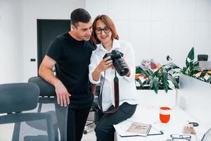 uomo nel nero Abiti Guardando fotografie su il femminile fotografo telecamera