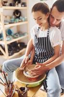 con sua fidanzato o marito. giovane femmina ceramista avere un' lavori in casa con fatto a mano argilla Prodotto. concezione di ceramica foto