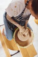 giovane femmina ceramista Lavorando di utilizzando ceramica ruota in casa e fabbricazione fatto a mano argilla Prodotto foto