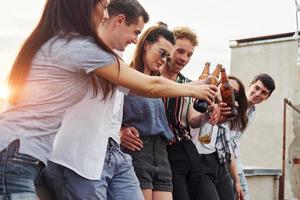 pendente su il bordo di il tetto con decora. gruppo di giovane persone nel casuale Abiti avere un' festa insieme a giorno foto