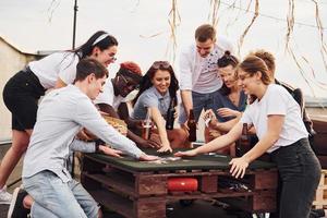 con delizioso Pizza. gruppo di giovane persone nel casuale Abiti avere un' festa a tetto insieme a giorno foto