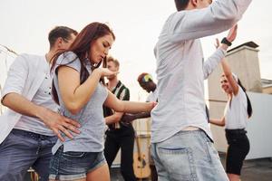 ricreazione volta. gruppo di giovane persone nel casuale Abiti avere un' festa a tetto insieme a giorno foto