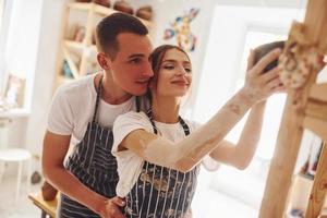 lavoro è fatto. con sua fidanzato o marito. giovane femmina ceramista in casa con finito fatto a mano argilla Prodotto. concezione di ceramica foto