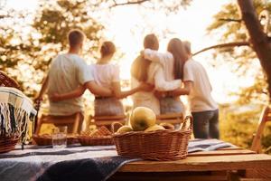 Abbracciare una persona ogni altro e guardare a tramonto. gruppo di giovane persone avere vacanza all'aperto nel il foresta. concezione di fine settimana e amicizia foto