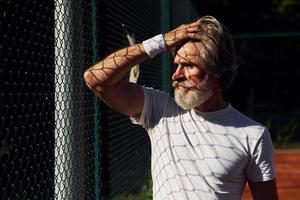 assunzione un' rompere. anziano moderno elegante uomo all'aperto su il allegro campo a giorno foto