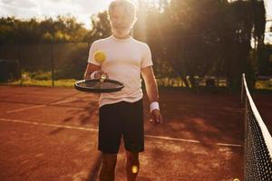 formazione volta. anziano moderno elegante uomo con racchetta all'aperto su tennis Tribunale a giorno foto