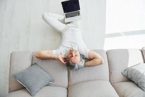 gode musica. anziano elegante moderno uomo con grigio capelli e barba in casa foto