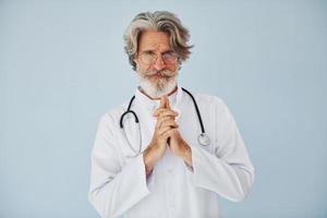 professionale positivo medico. anziano elegante moderno uomo con grigio capelli e barba in casa foto