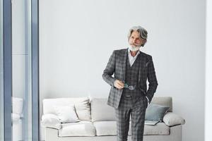 concezione di bellissimo stile. anziano elegante moderno uomo con grigio capelli e barba in casa foto
