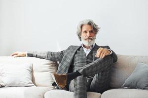 concezione di bellissimo stile. anziano elegante moderno uomo con grigio capelli e barba in casa foto