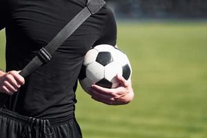 calcio giocatore su il campo. allegro giovane tipo nel nero camicia e pantaloni all'aperto a giorno foto