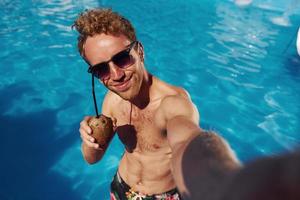 positivo giovane uomo avere un' riposo all'aperto nel nuoto piscina a giorno foto