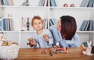 madre con figlia festeggiare Pasqua vacanze insieme. vernici uova foto