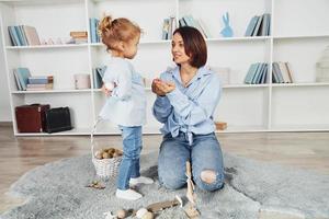 madre con figlia festeggiare Pasqua vacanze insieme. poco ragazza dando uova foto