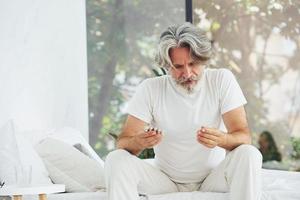 concezione di malattia e virus. anziano elegante moderno uomo con grigio capelli e barba in casa foto