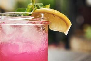 rosa colorato liquido con Limone. vicino su Visualizza di fresco estate alcolizzato cocktail su il di legno tavolo foto