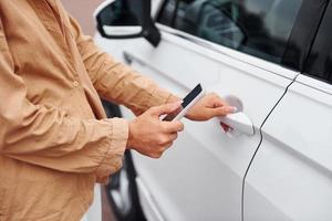 si apre il porta. alla moda bellissimo giovane donna e sua moderno automobile foto