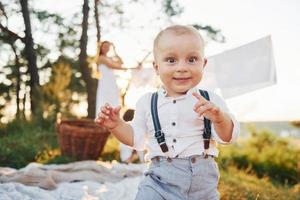 bianca Abiti sospeso su il corda per asciutto. giovane madre con sua poco figlia e figlio è all'aperto nel il foresta. bellissimo luce del sole foto