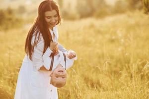 giovane madre con sua poco figlio è all'aperto nel il agricolo campo. bellissimo luce del sole foto