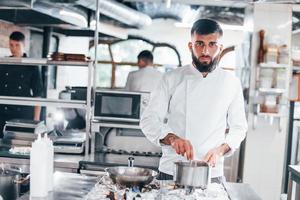 cuochi delizioso la minestra. capocuoco nel bianca uniforme cucinando cibo a cucina. occupato giorno a opera foto